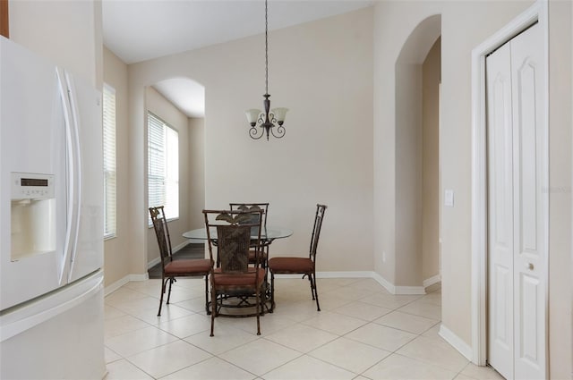 dining area with arched walkways, a chandelier, baseboards, and light tile patterned floors
