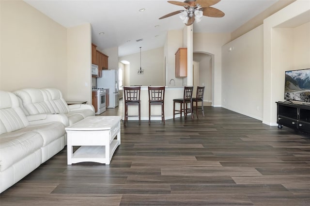living area featuring arched walkways, lofted ceiling, a ceiling fan, dark wood-style flooring, and baseboards