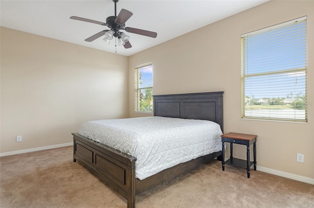 bedroom with light carpet, baseboards, and a ceiling fan