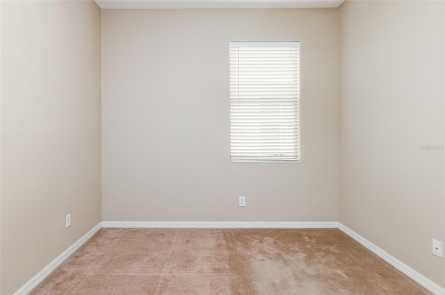 empty room featuring light carpet and baseboards