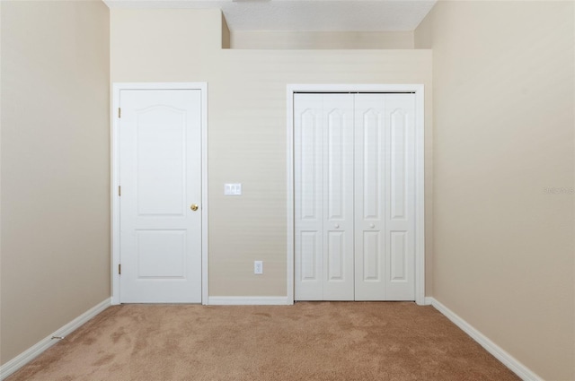 unfurnished bedroom featuring carpet, baseboards, and a closet