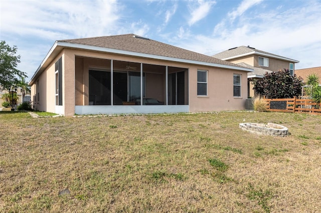 rear view of property featuring a sunroom, stucco siding, and an outdoor fire pit