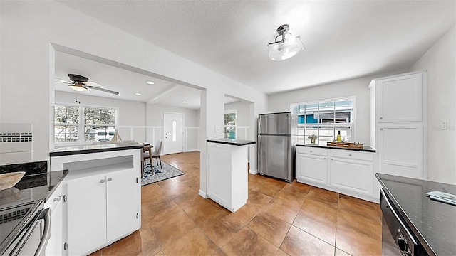 1402 Freemont St S, Gulfport, FL 33707 - kitchen with stainless steel appliances, dark countertops, white cabinetry, ceiling fan, and light tile patterned flooring