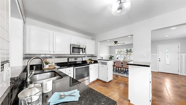 1402 Freemont St S, Gulfport, FL 33707 - kitchen with appliances with stainless steel finishes, a sink, white cabinetry, backsplash, and a ceiling fan