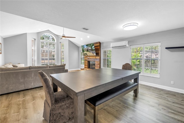 13785 Oak Forest Blvd S, Seminole, FL 33776 - dining area featuring a wall mounted air conditioner, a stone fireplace, light wood-style flooring, lofted ceiling, and visible vents