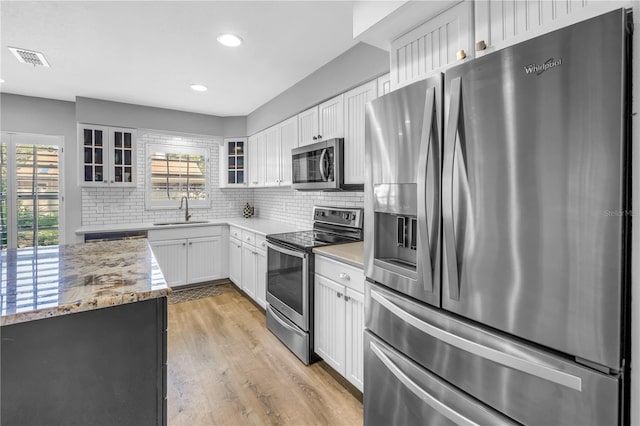 13785 Oak Forest Blvd S, Seminole, FL 33776 - kitchen with visible vents, appliances with stainless steel finishes, light wood-type flooring, a sink, and glass insert cabinets