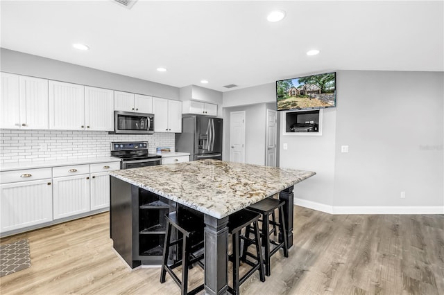 13785 Oak Forest Blvd S, Seminole, FL 33776 - kitchen featuring a breakfast bar area, a center island, light wood finished floors, stainless steel appliances, and white cabinetry