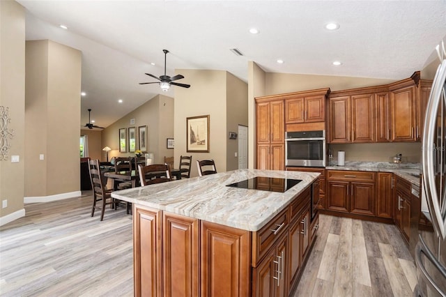 kitchen featuring appliances with stainless steel finishes, a ceiling fan, light wood-style flooring, and vaulted ceiling