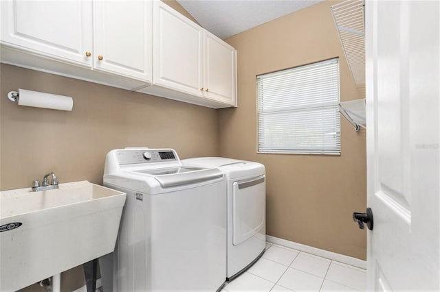 clothes washing area with washing machine and clothes dryer, a sink, baseboards, light tile patterned flooring, and cabinet space