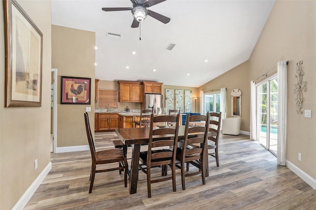 dining space with a ceiling fan, visible vents, lofted ceiling, and light wood-style floors