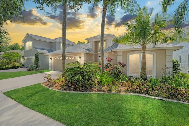 view of front of house featuring a front yard, a garage, stucco siding, and concrete driveway