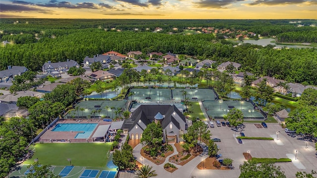 aerial view at dusk with a forest view, a residential view, and a water view