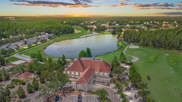 aerial view at dusk featuring a residential view, a water view, and golf course view