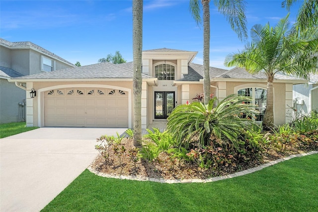 view of front of property with stucco siding, a garage, driveway, french doors, and a front yard