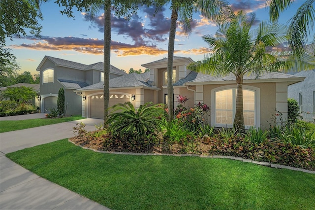 view of front facade with an attached garage, a front lawn, driveway, and stucco siding