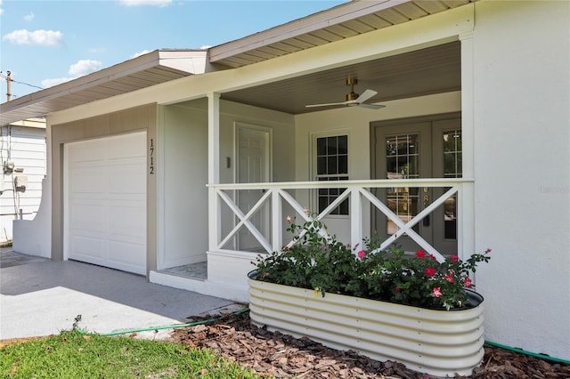 view of exterior entry with stucco siding, ceiling fan, and a garage