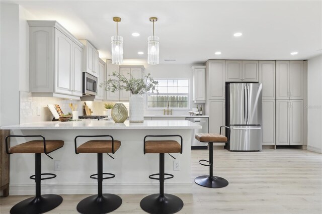 kitchen featuring decorative backsplash, stainless steel appliances, a breakfast bar, a peninsula, and light countertops