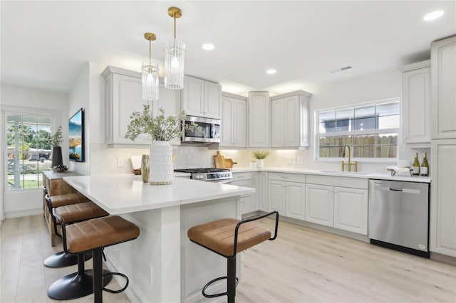 kitchen featuring a sink, stainless steel appliances, a breakfast bar, visible vents, and a peninsula