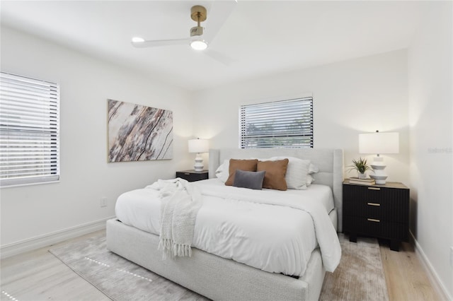 bedroom featuring a ceiling fan, light wood-style flooring, and baseboards