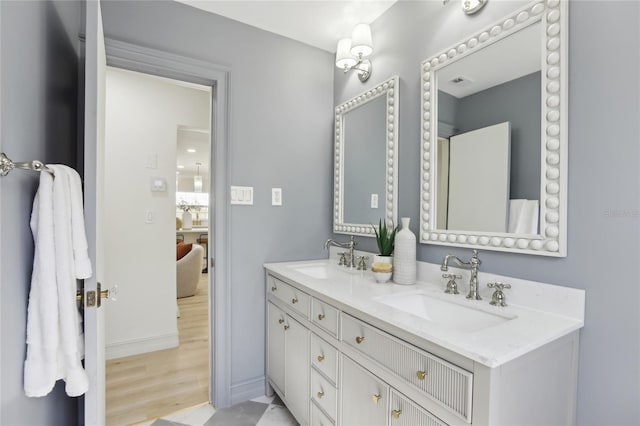 bathroom featuring baseboards, wood finished floors, double vanity, and a sink