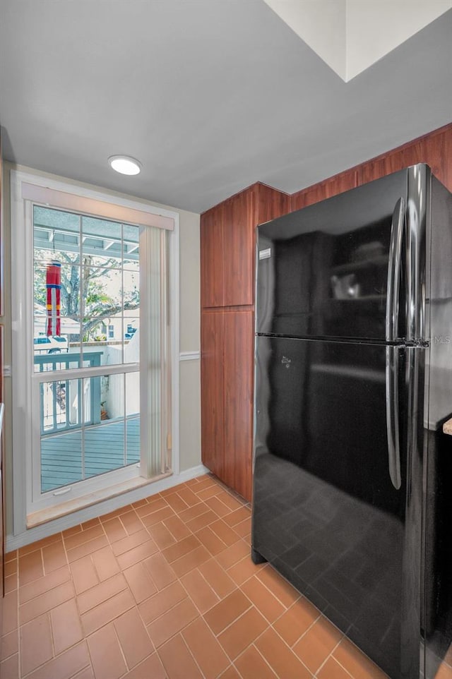 5115 S Jules Verne Ct, Tampa, FL 33611 - kitchen featuring tile patterned flooring, freestanding refrigerator, and brown cabinetry