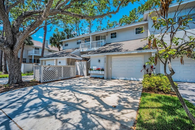 5115 S Jules Verne Ct, Tampa, FL 33611 - view of front of home with a balcony, stucco siding, driveway, an attached garage, and fence