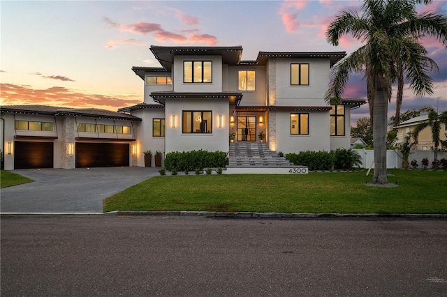 contemporary house with stucco siding, driveway, fence, and a lawn