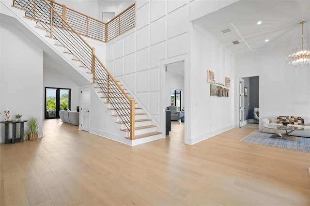 entrance foyer with light wood-style flooring, a high ceiling, stairs, and visible vents