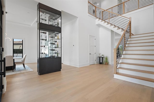 stairway featuring wood finished floors, a towering ceiling, and baseboards