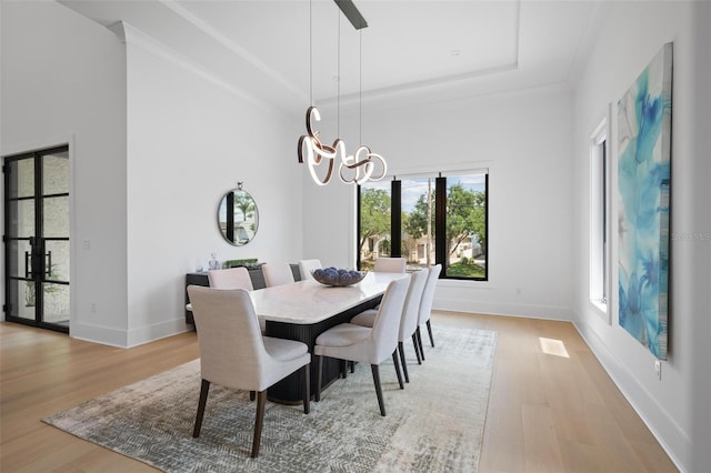 dining room featuring a tray ceiling, light wood-style floors, and baseboards