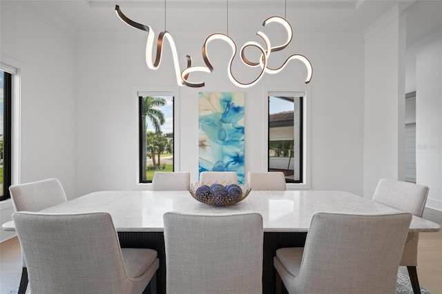 dining area with plenty of natural light, ornamental molding, wood finished floors, and an inviting chandelier