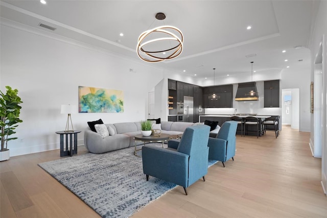 living area featuring light wood-style flooring, visible vents, recessed lighting, and crown molding