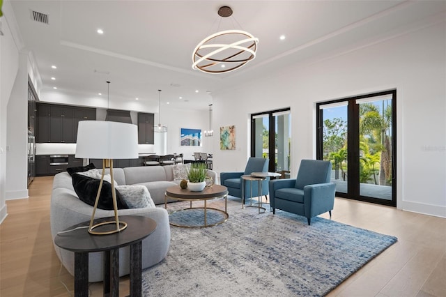 living room featuring recessed lighting, a tray ceiling, visible vents, and an inviting chandelier