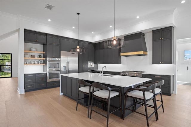kitchen with a sink, visible vents, light countertops, appliances with stainless steel finishes, and premium range hood
