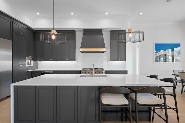 kitchen featuring a kitchen breakfast bar, light countertops, stainless steel refrigerator, a sink, and custom range hood