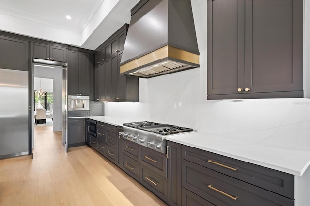 kitchen with light wood-style flooring, custom exhaust hood, recessed lighting, light countertops, and appliances with stainless steel finishes