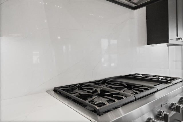 details featuring backsplash, stovetop, and light stone counters