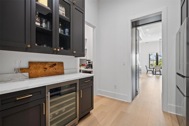 bar featuring baseboards, beverage cooler, and light wood finished floors