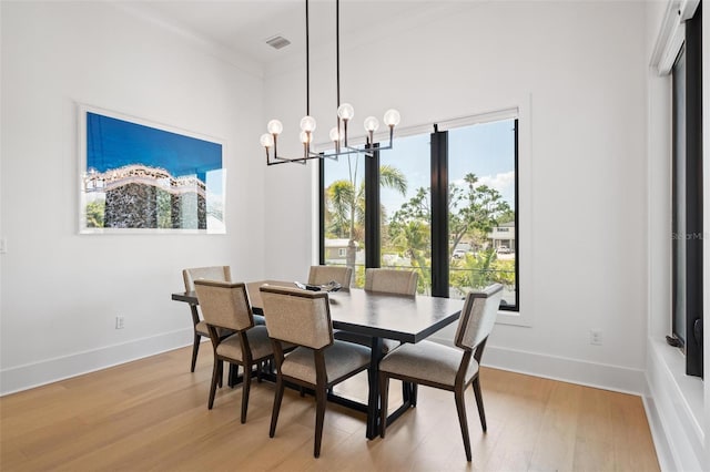 dining space featuring light wood-type flooring, baseboards, visible vents, and an inviting chandelier