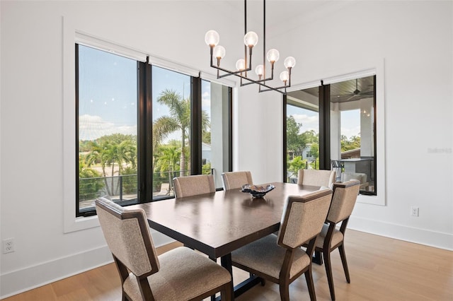 dining area with light wood-type flooring, a wealth of natural light, and a notable chandelier