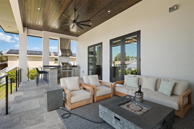 view of patio featuring an outdoor kitchen, a ceiling fan, a bar, area for grilling, and an outdoor living space with a fire pit