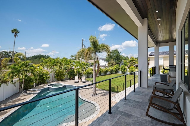 balcony featuring a pool with connected hot tub