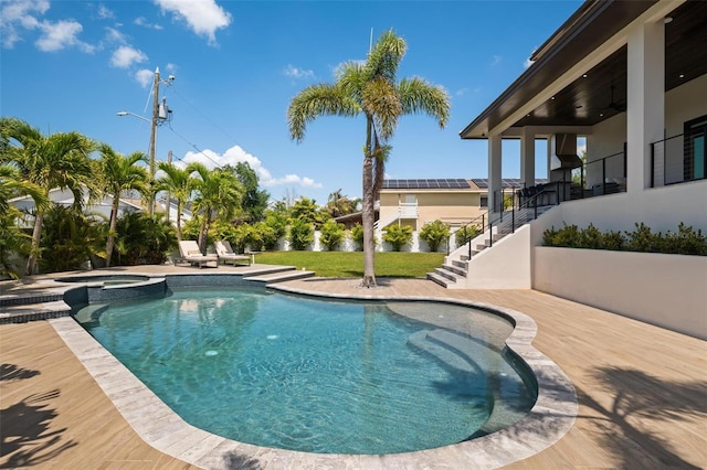 view of swimming pool with a yard, a pool with connected hot tub, a patio, and stairway