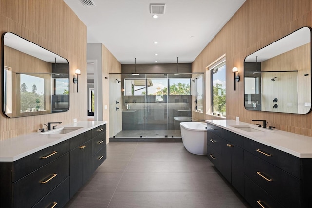 bathroom with two vanities, a shower stall, visible vents, and a sink