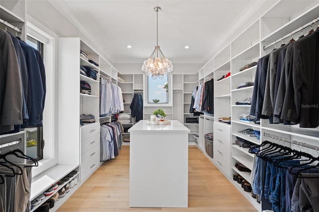 spacious closet with light wood-style flooring and an inviting chandelier