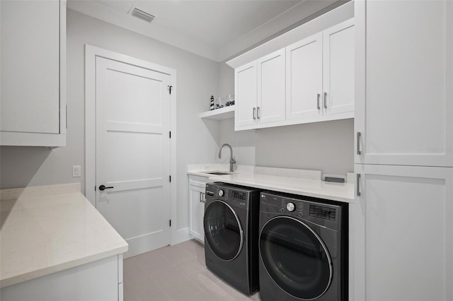 laundry area featuring visible vents, light tile patterned floors, a sink, separate washer and dryer, and cabinet space