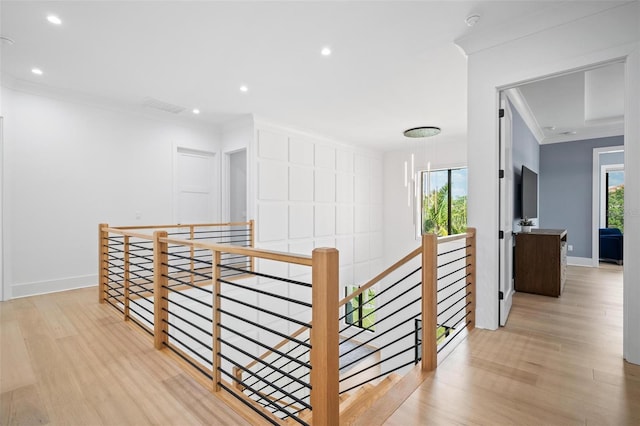 corridor with wood finished floors, visible vents, an upstairs landing, and crown molding