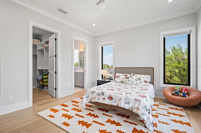 bedroom featuring light wood finished floors, visible vents, a spacious closet, and multiple windows