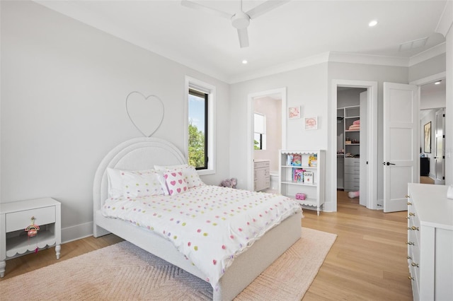 bedroom with a walk in closet, recessed lighting, ornamental molding, and a closet