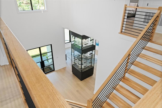 stairs with baseboards, wood finished floors, and a high ceiling